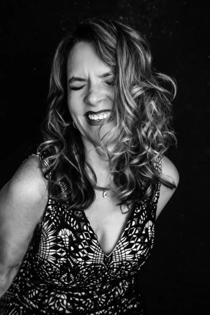 a black and white image of a woman laughing and showing personality in a photography studio