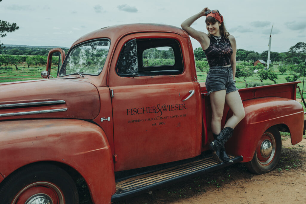 a girl standing by a red truck posing fo rher senior photos