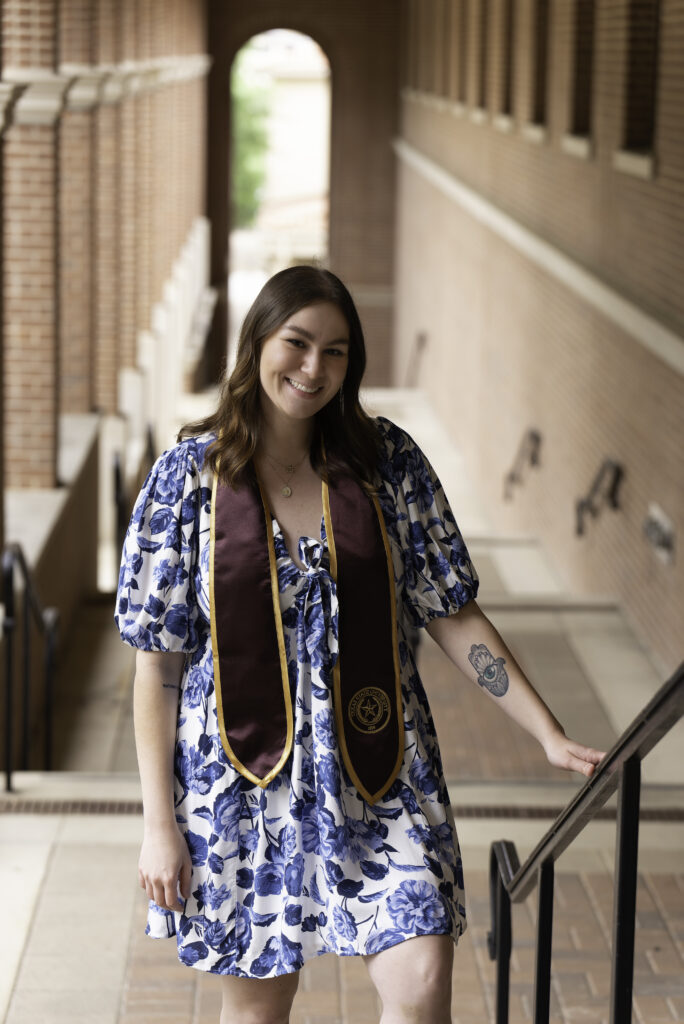 a girl standing on stairs with a high school graduation sash